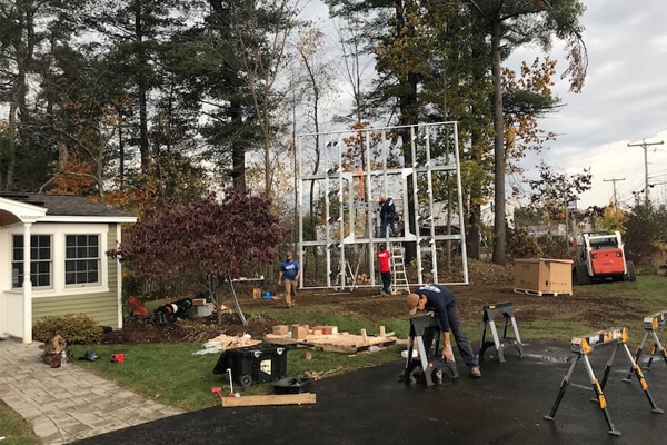 Children playing on outdoor gym equipment in a residential backyard with trees and shed.