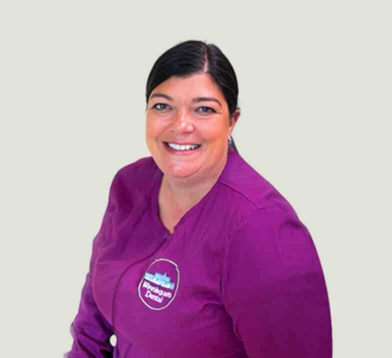 Smiling dental professional wearing purple Winnisquam Dental uniform against neutral background.