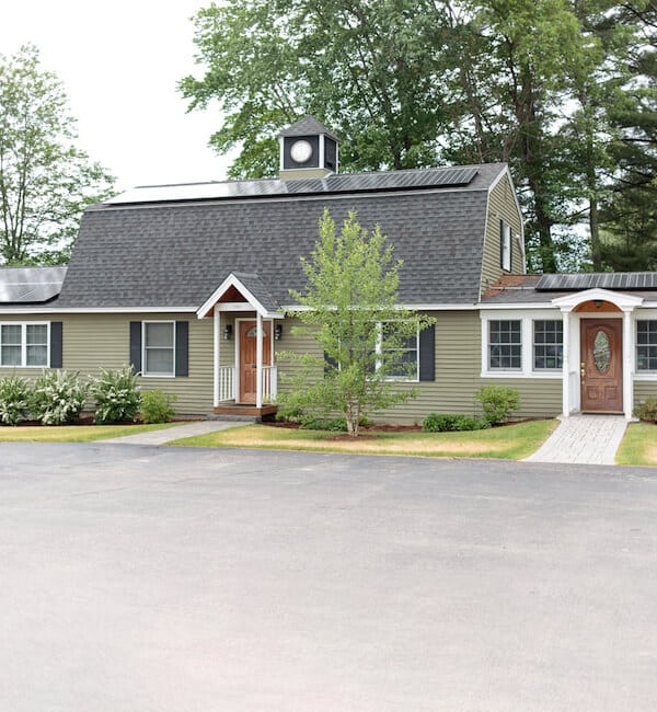 Modern single-story dental office building with gray siding, white trim, and professional landscaping surrounded by trees.