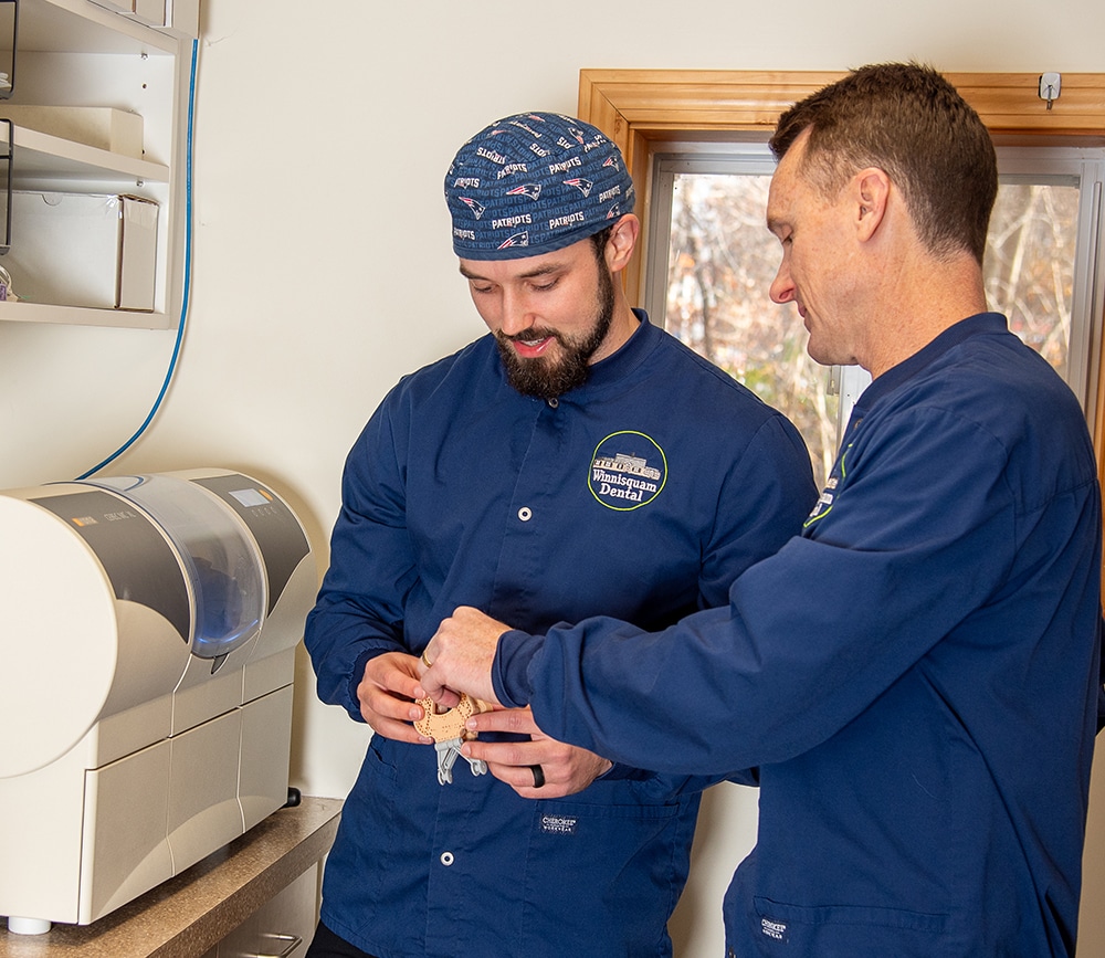 Two dental professionals in blue uniforms reviewing patient information in a dental office.