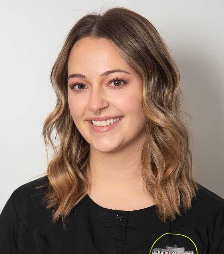 Young woman smiling at camera wearing black shirt against white background, professional headshot.