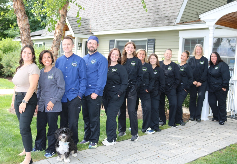 Winnisquam Dental team standing outdoors in front of the office, with a dog in the front row