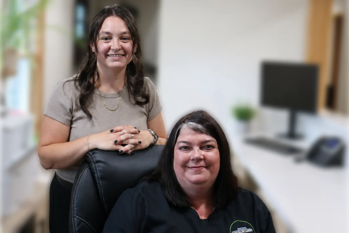 Two Winnisquam Dental front desk staff members smiling at the reception area